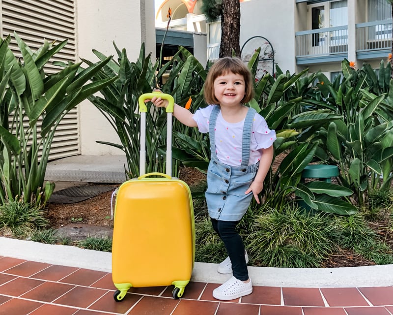 Young girl standing with yellow suitcase