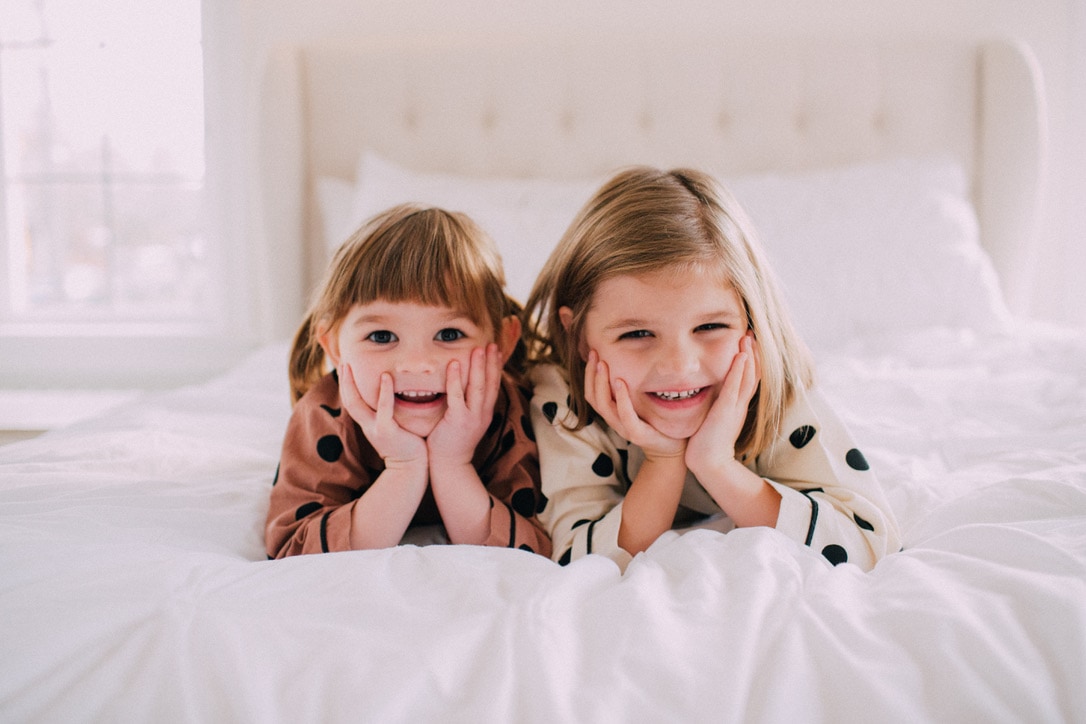 Two girls in polkadot pajamas laying on bed
