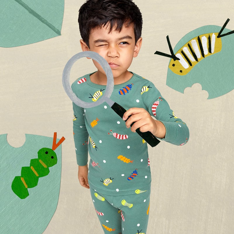 A boy wearing pajamas and holding a magnifying glass