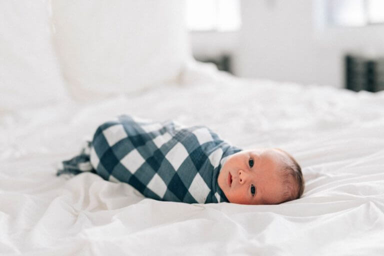 a swaddle baby laying on the bed