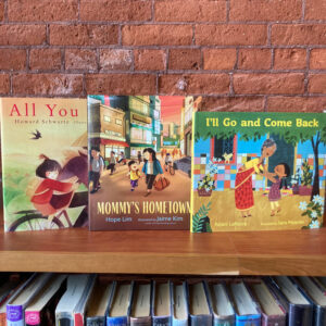 three children's books on top of a wooden bookshelf in front of a brick wall