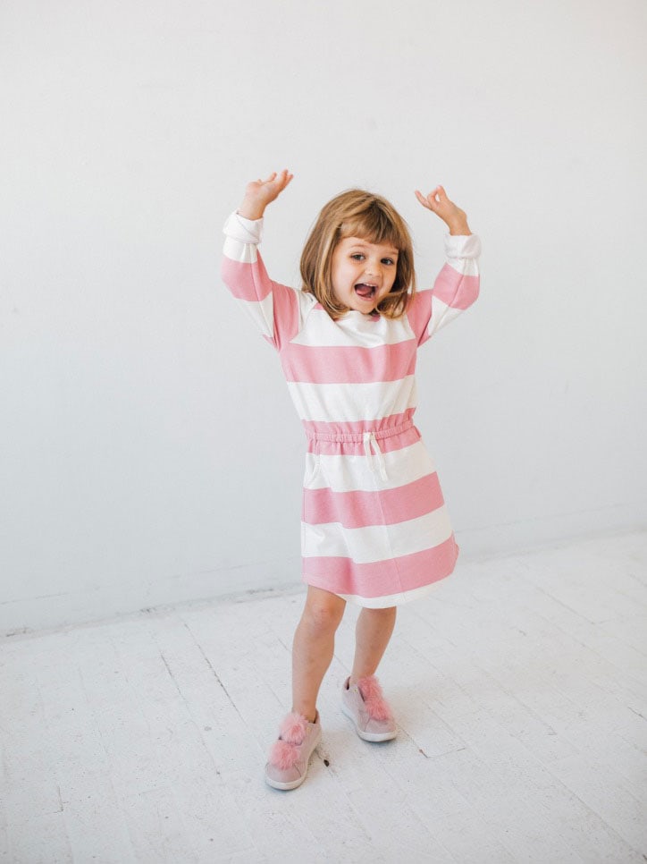 smiling little girl wearing a pink and white striped dress